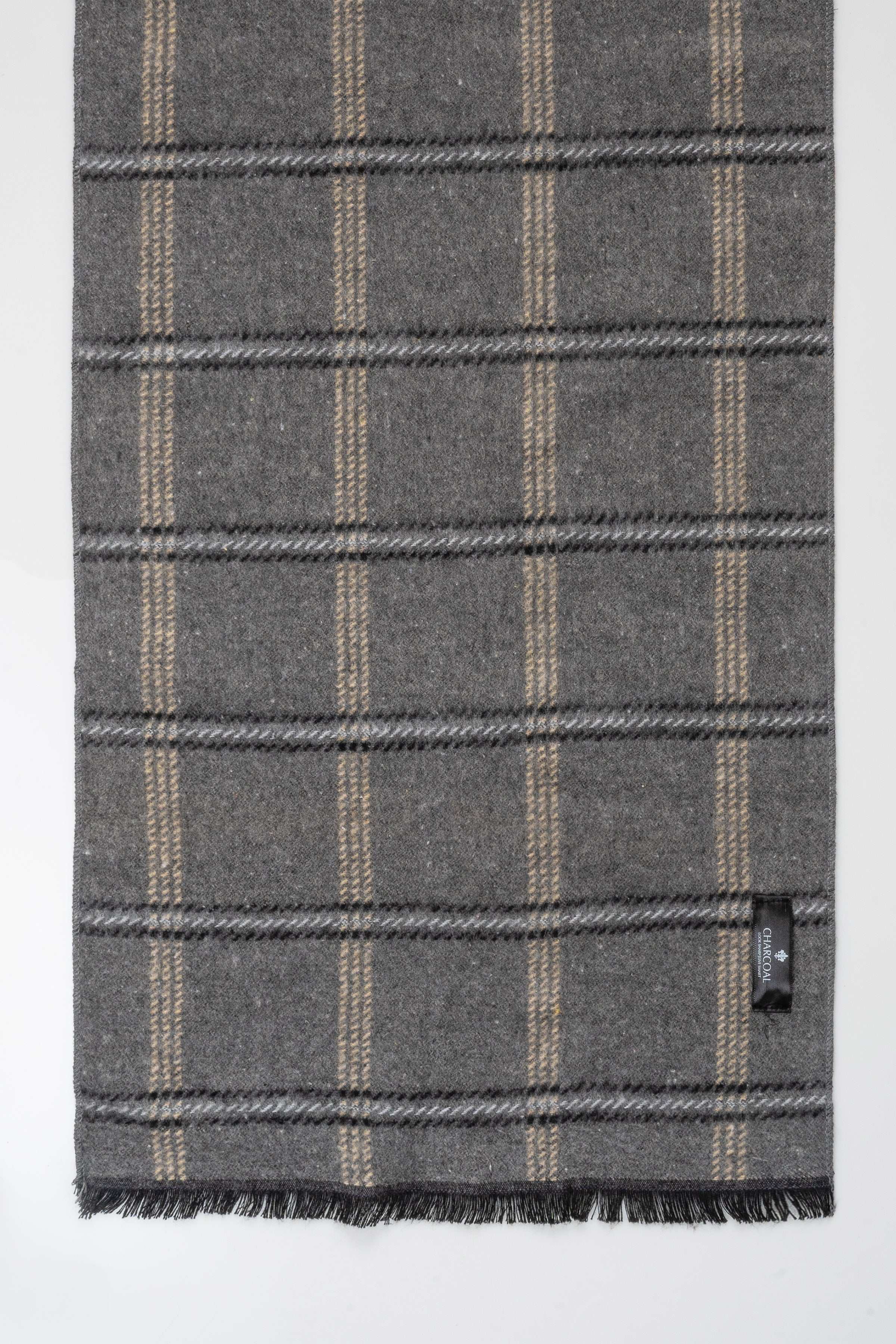 Plaid scarf close-up in dark gray with tan windowpane checks and fringed edge at bottom.