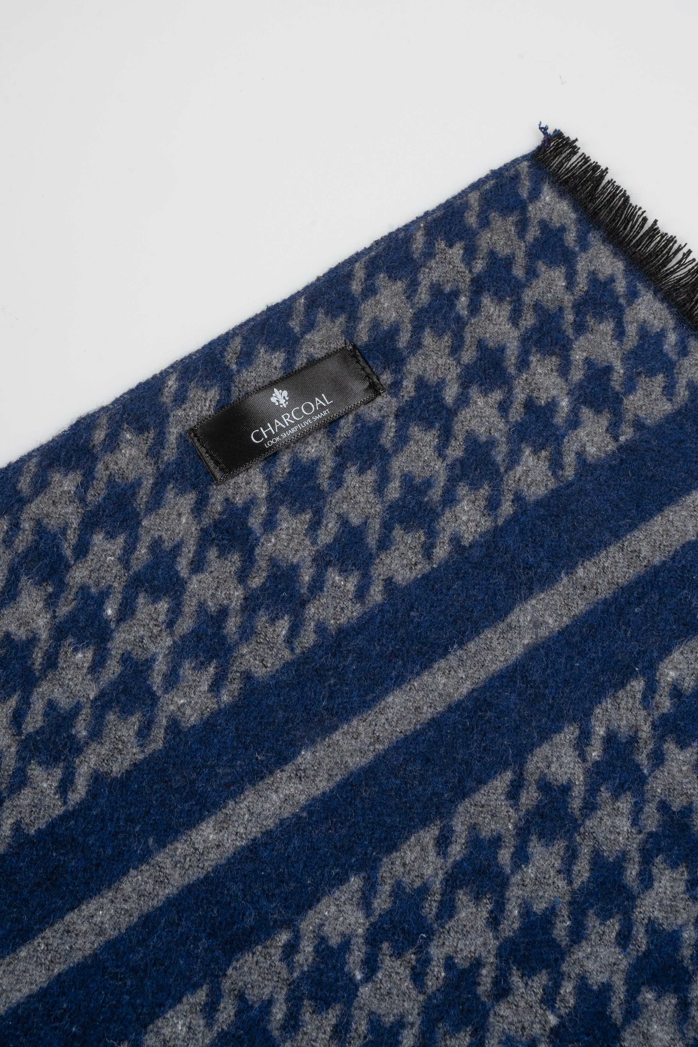 Blue houndstooth scarf close-up with brand label and striped edge, fringed trim