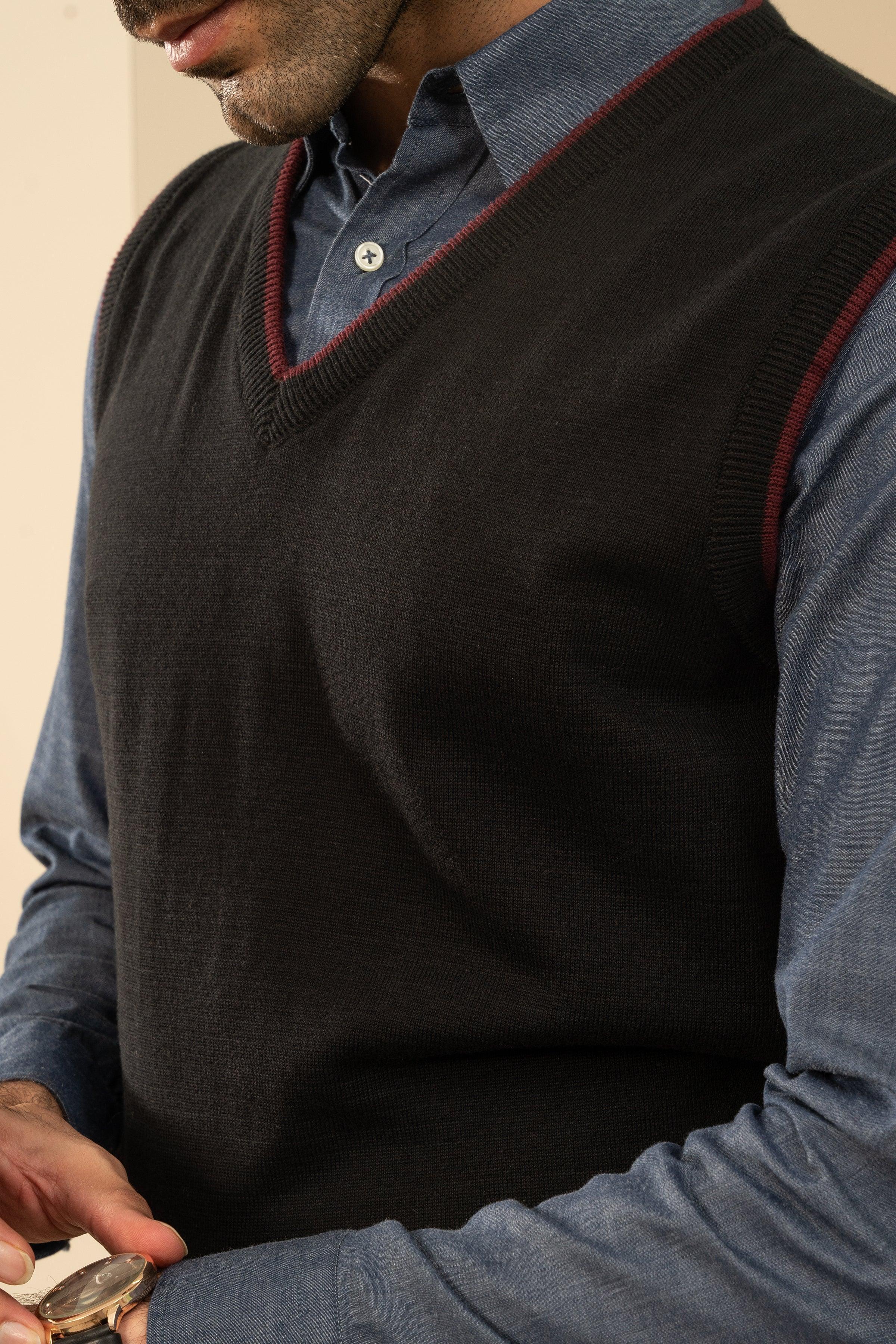 Black sleeveless sweater vest close-up with maroon V-neck trim and ribbed cuffs
